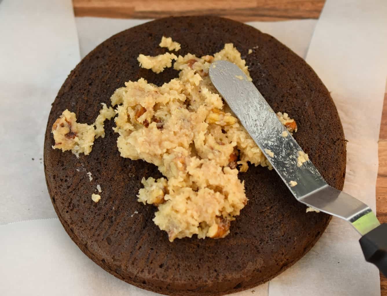 keto German chocolate cake being layered with pecan coconut frosting