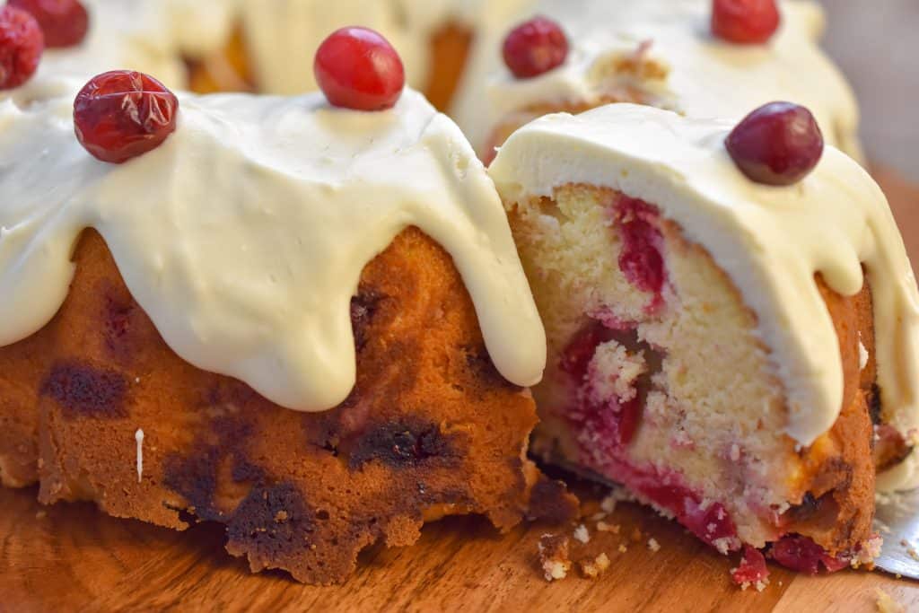 keto cranberry cake being sliced on wood cake stand