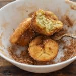 keto mini churros with a bite in bowl of cinnamon sugar