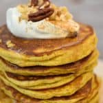 keto pumpkin pancakes topped with cream cheese icing close up on a white plate