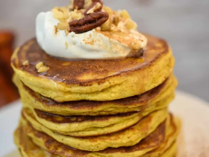 keto pumpkin pancakes topped with cream cheese icing close up on a white plate