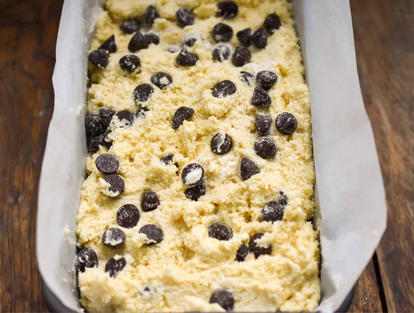 keto chocolate chip pound cake batter inside a parchment lined loaf pan