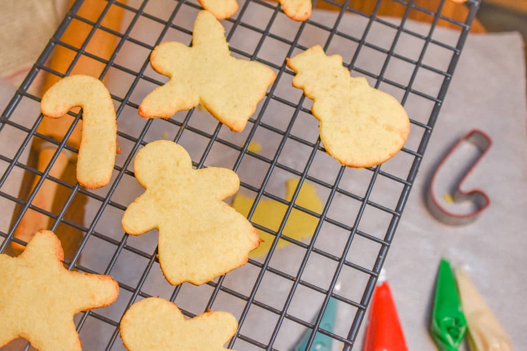 Keto Rolled Sugar Cookies on cooling rack with cookie cutter and icing in background