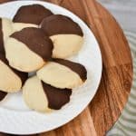 keto black and white cookies on white plate and wood stand off center