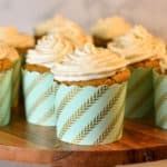 keto carrot cupcakes with cream cheese frosting on a wood cake stand
