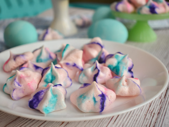keto french meringues on white plate with blue dyed eggs in background