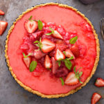keto strawberry rhubarb cheesecake top view whole tart on a grey counter