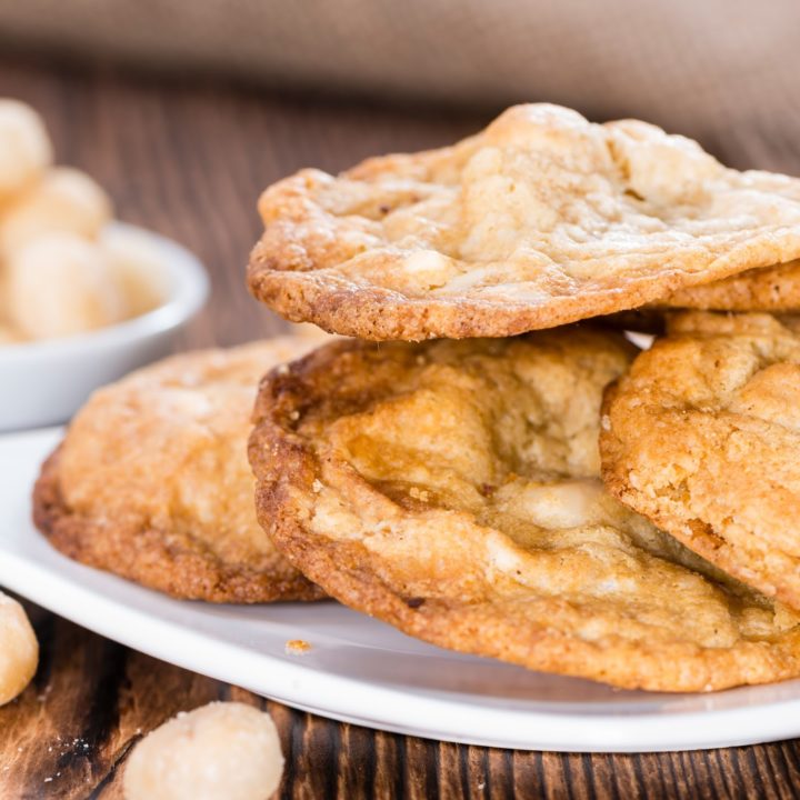 keto white chocolate macademia cookies on white plate with scattered white chocolate chips.