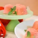 strawberry jello cream cheese fat bombs on green pedestal with mint leaves and red polka dot towel