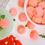 strawberry jello cream cheese fat bombs on white plate with red polka dot towel and mint leaves