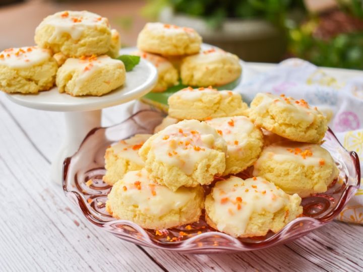 keto orange cookies on pink glass plate and white pedestal in the background