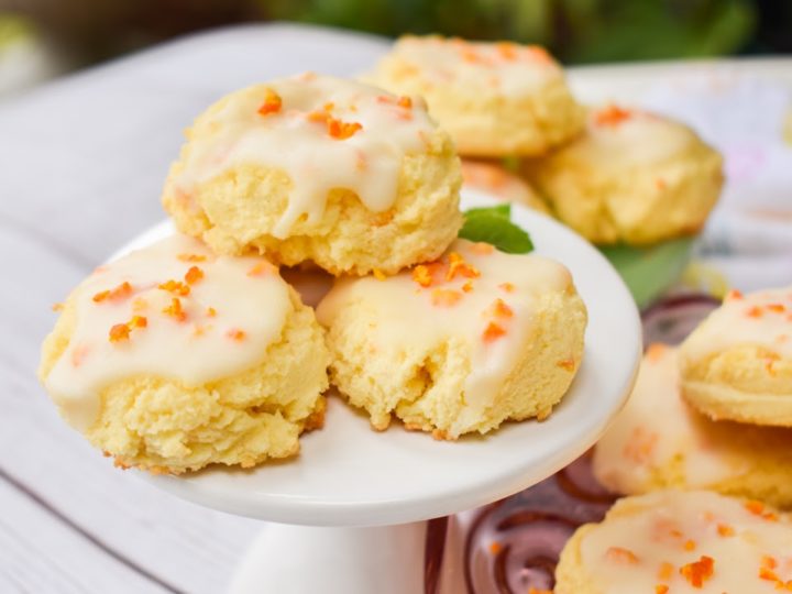 keto orange cookies on white pedestal with more cookies in the background