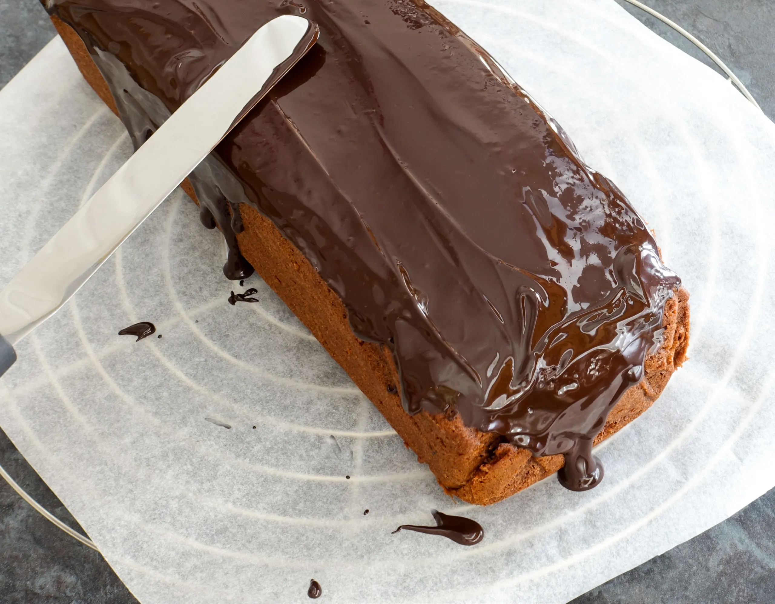 keto sour cream chocolate pound cake with chocolate ganache being smoothed over the top