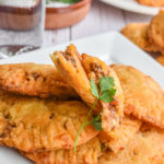 keto ground beef empanadas on white plate up close with more empanandas in the background
