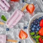 keto berries and cream popsicles on ice and white bowl with berries and mint up close
