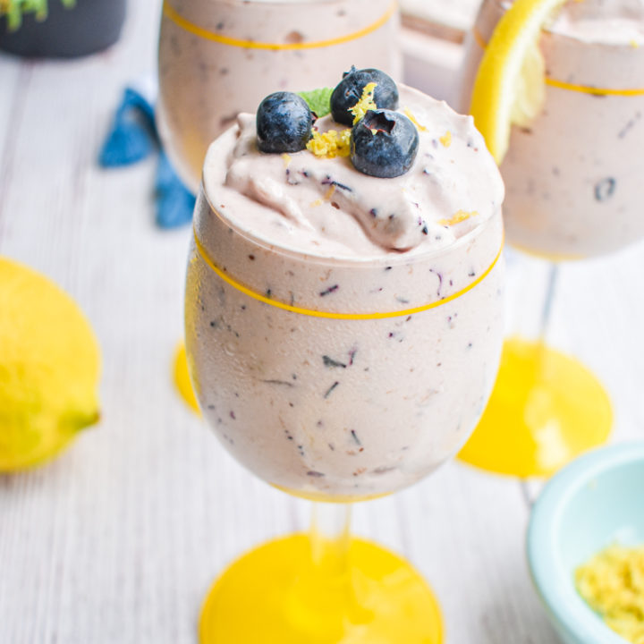 keto blueberry cheesecake mousse in a glass cup with yellow rim and base with lemon in the background