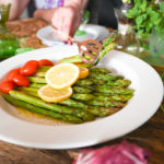 low carb asparagus salad being served with copper salad tongs