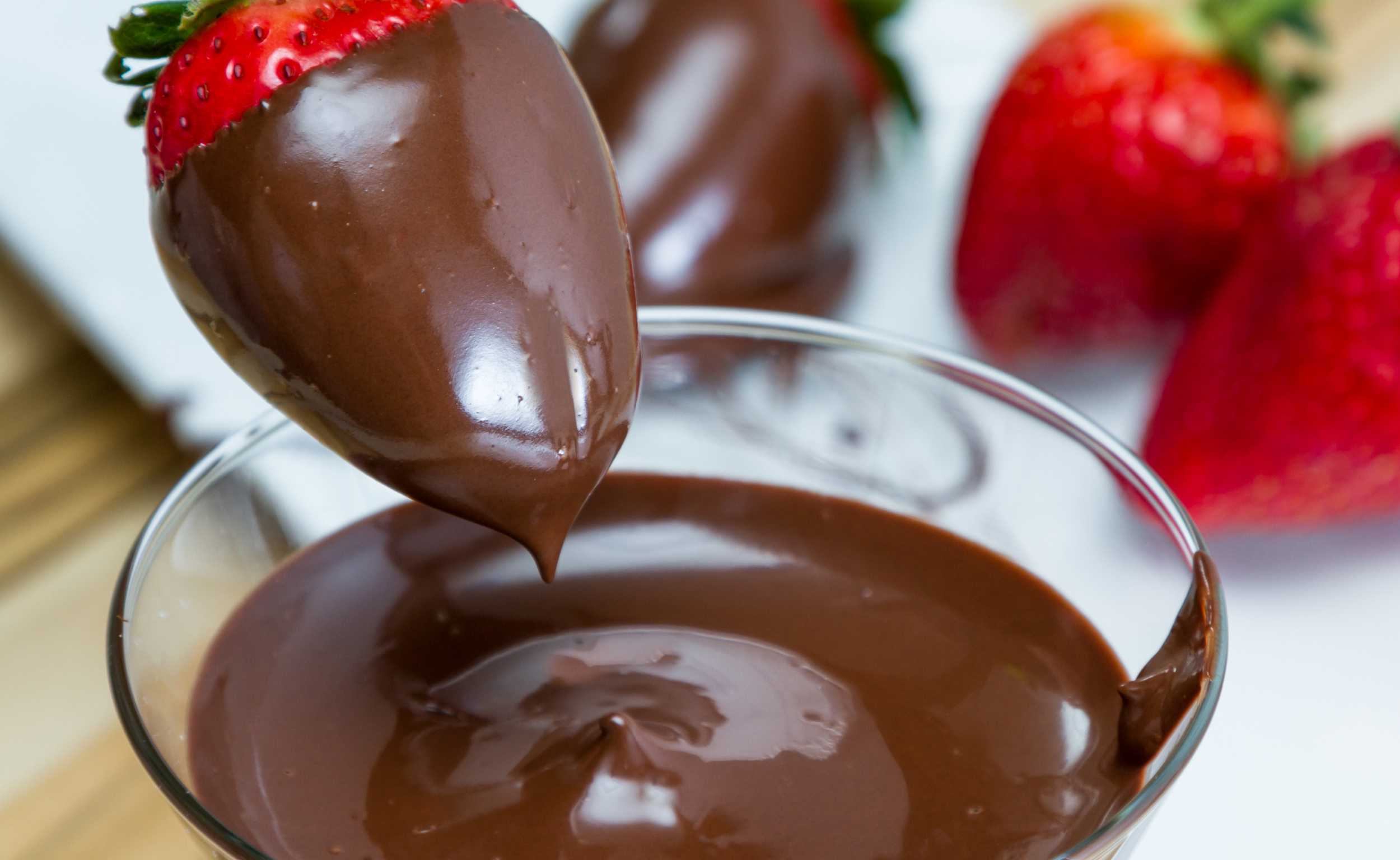 dipping fresh strawberries in dark keto-friendly chocolate