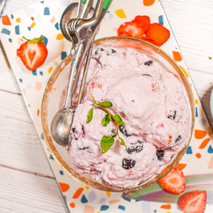 5 minute keto berry ice cream in gold bowl with scoop and topped