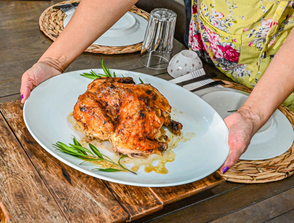 Keto Cuban Mojo Chicken on white plate being placed on wood trivet on table