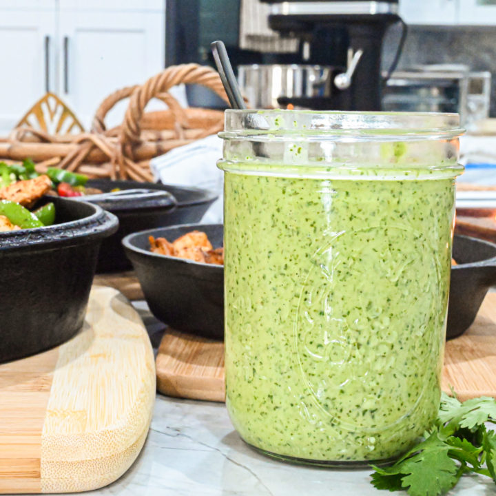 keto spicy cilantro garlic sauce in mason jar up close with cast iron skillets in background