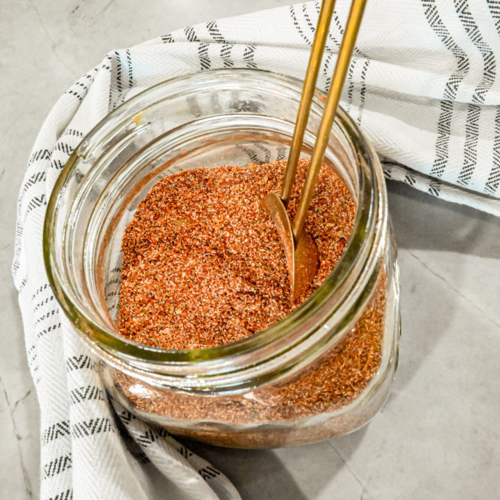 Keto fajita seasoning in glass jar with white and grey striped towel