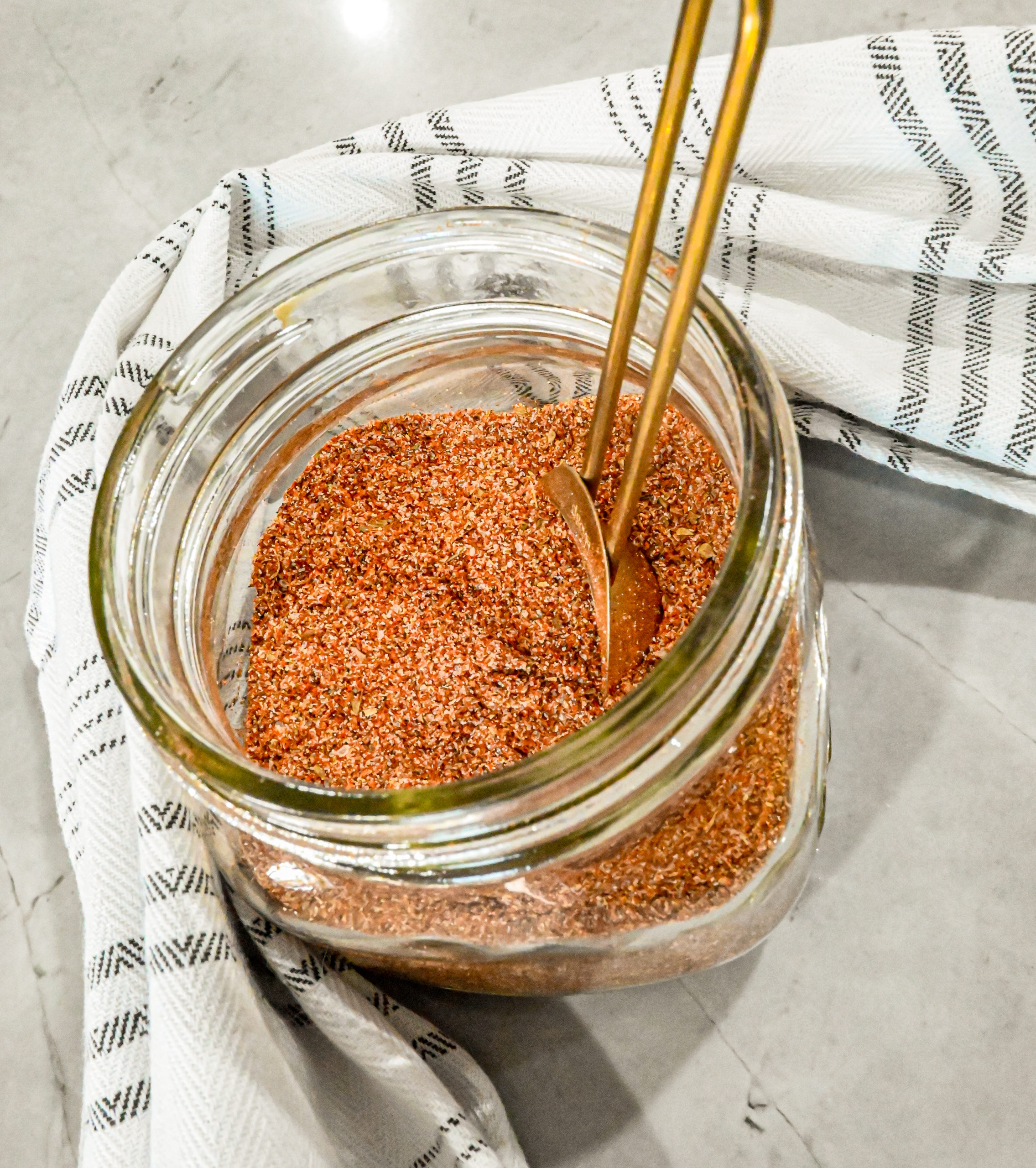 Keto fajita seasoning in glass jar with white and grey striped towel