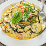 keto baked feta zucchini served in large white dish topped with fresh basil up close