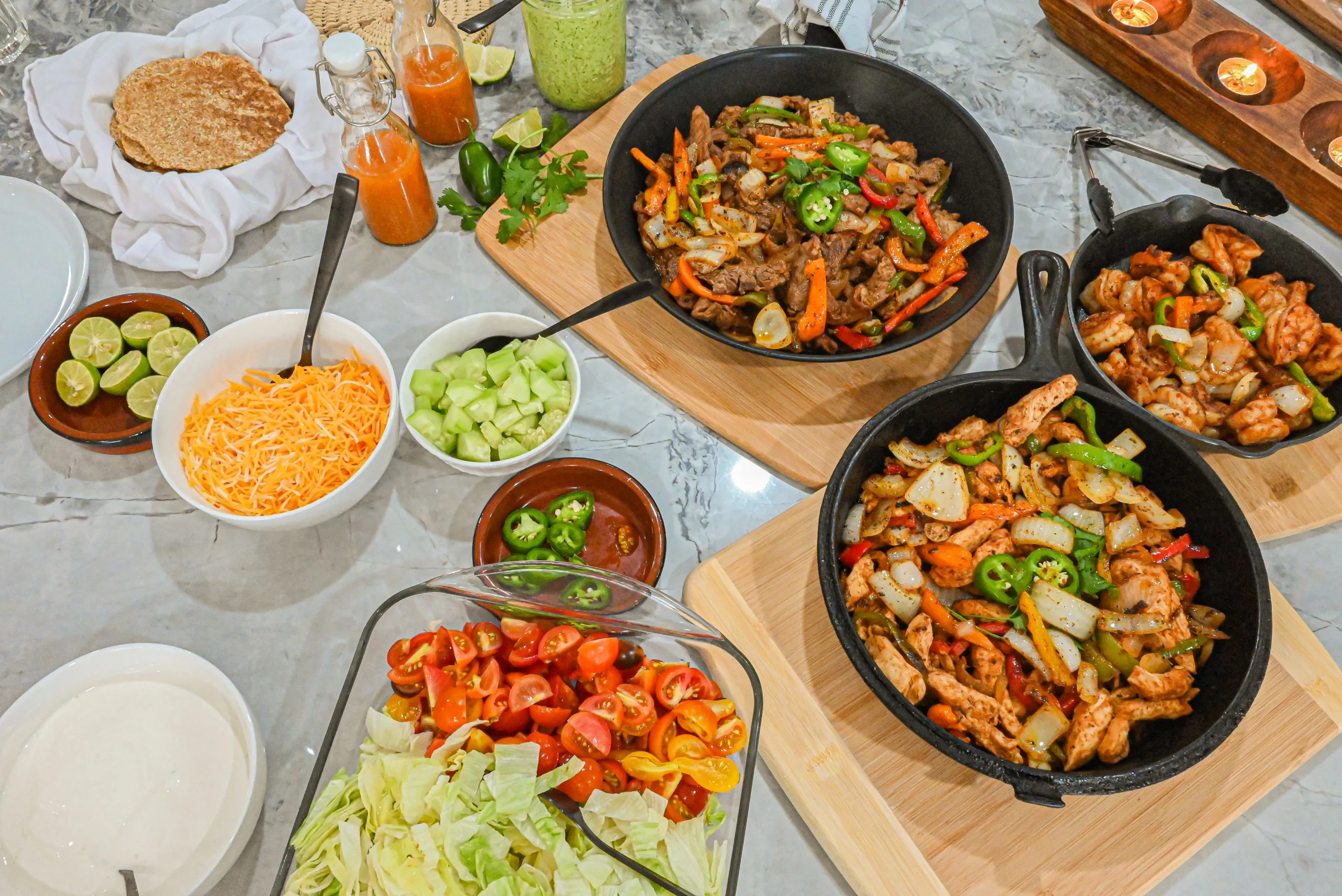 keto fajitas in skillets on counter with various sides surrounding