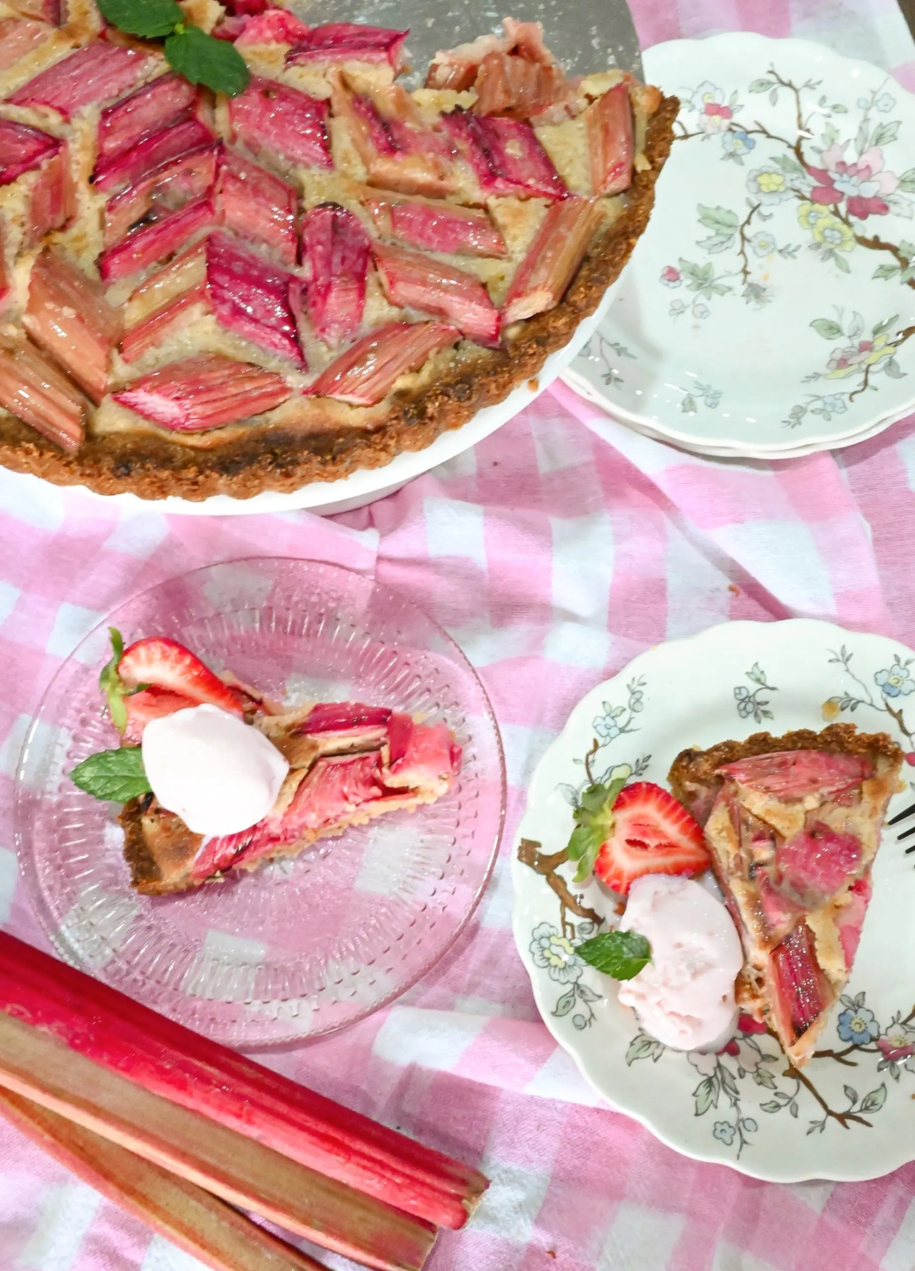 keto rhubarb tart on cake stand and sliced on a clear pink dish and floral white dish
