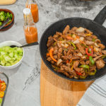 keto steak fajitas in cast iron skillet with various toppins on the side