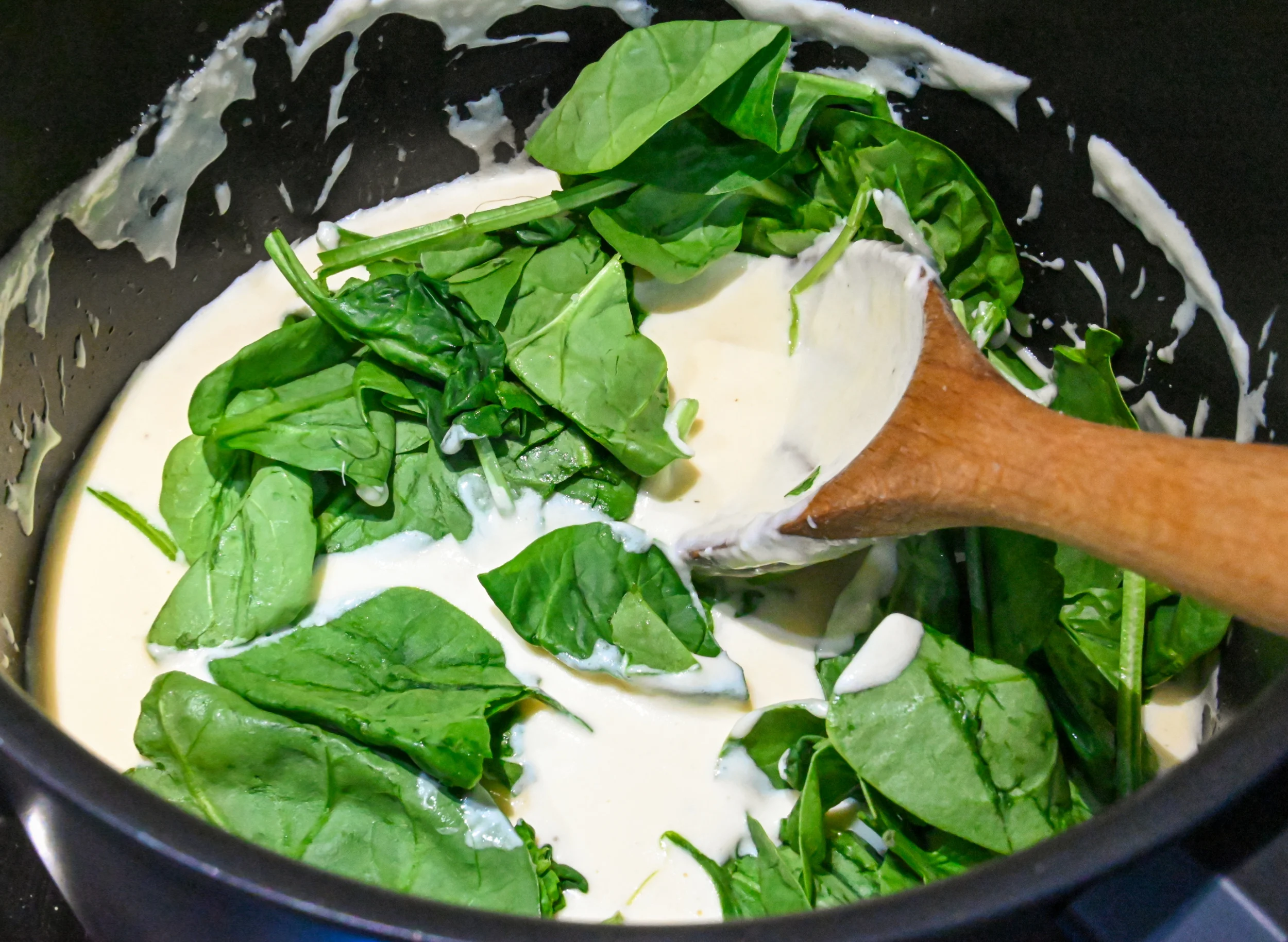 fresh spinach being added to the base of low carb spinach soup