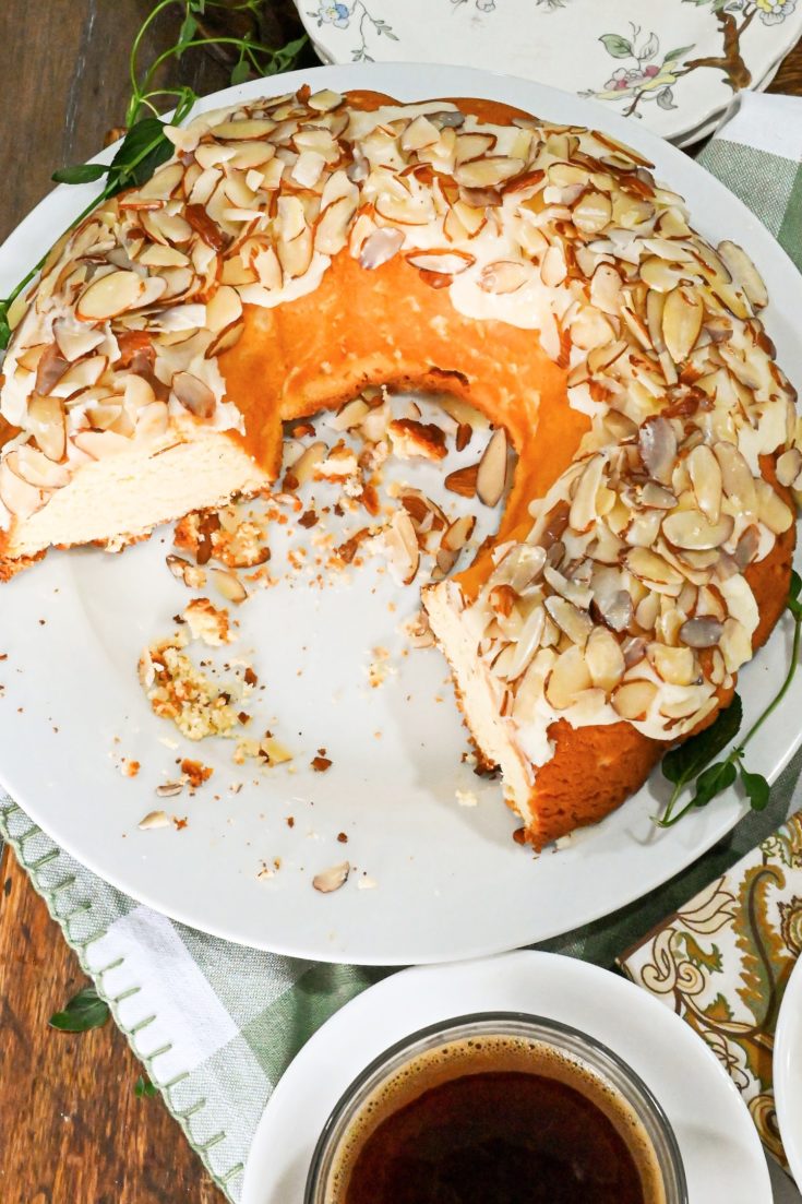 keto almond cake with slices missing on a white cake stand