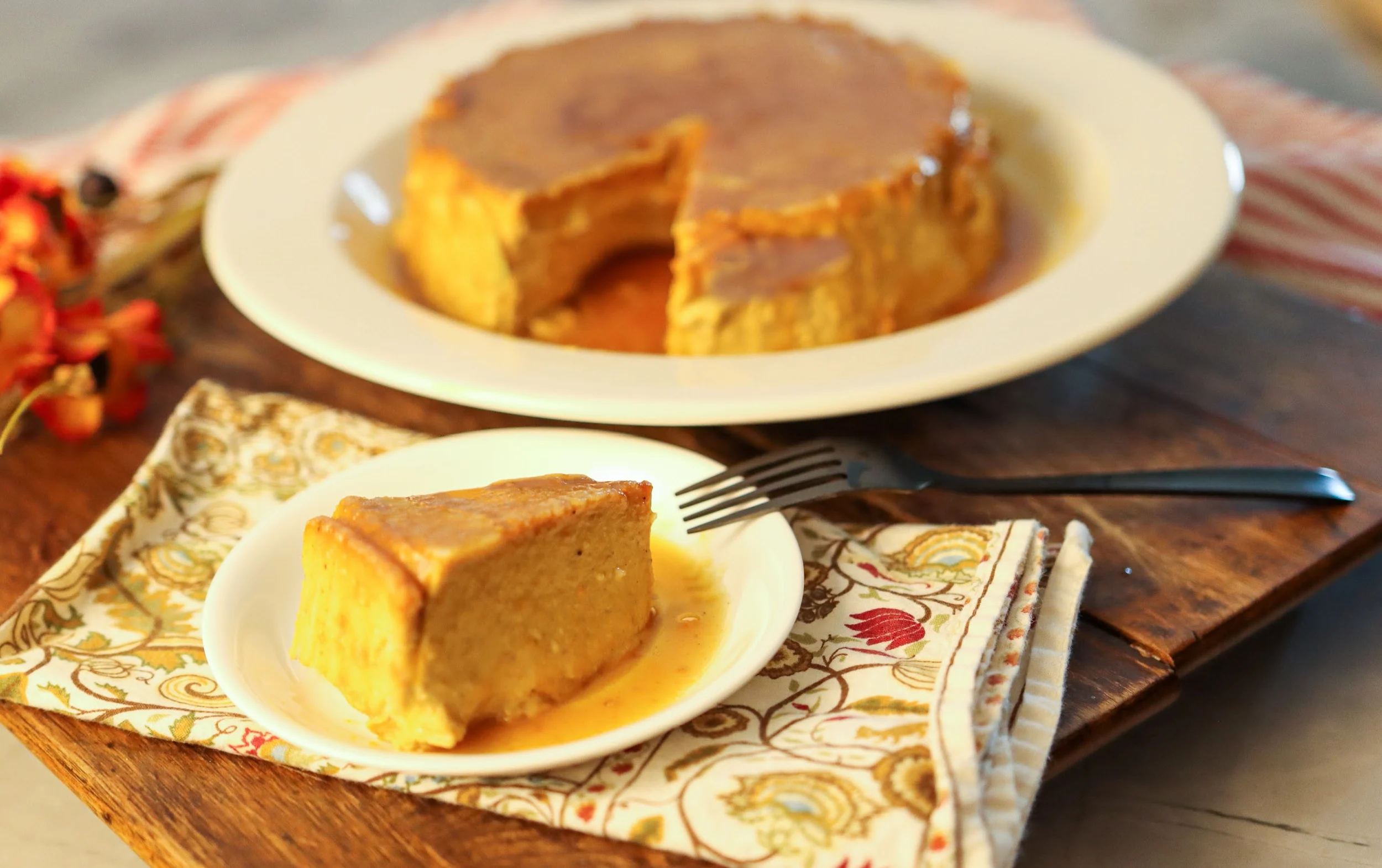 keto pumpkin flan sliced and ready to serve on a wood board with a fall napkin underneath