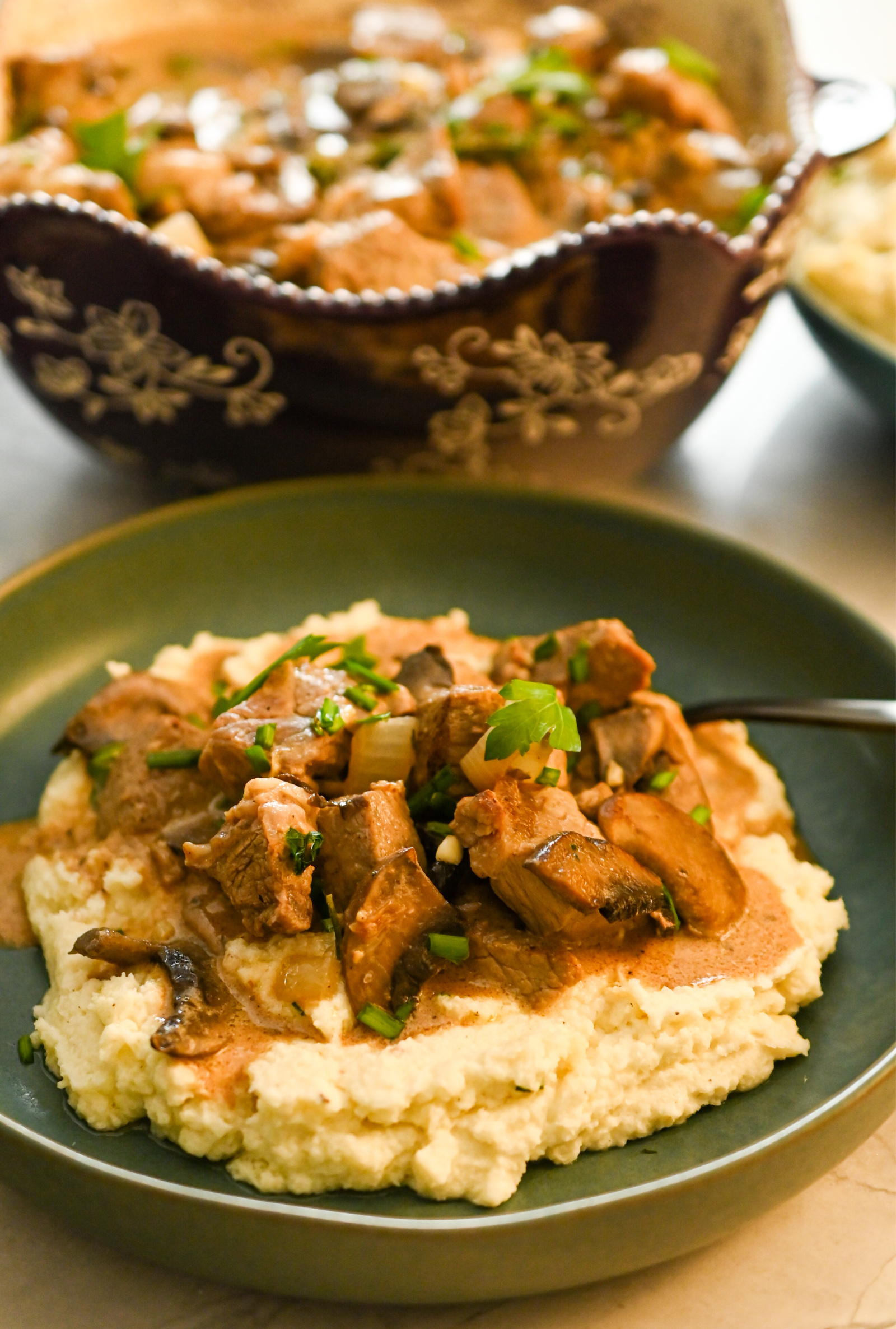 keto ribeye stroganoff served in a teal shallow bowl and a large brown bowl with the stroganoff on the side