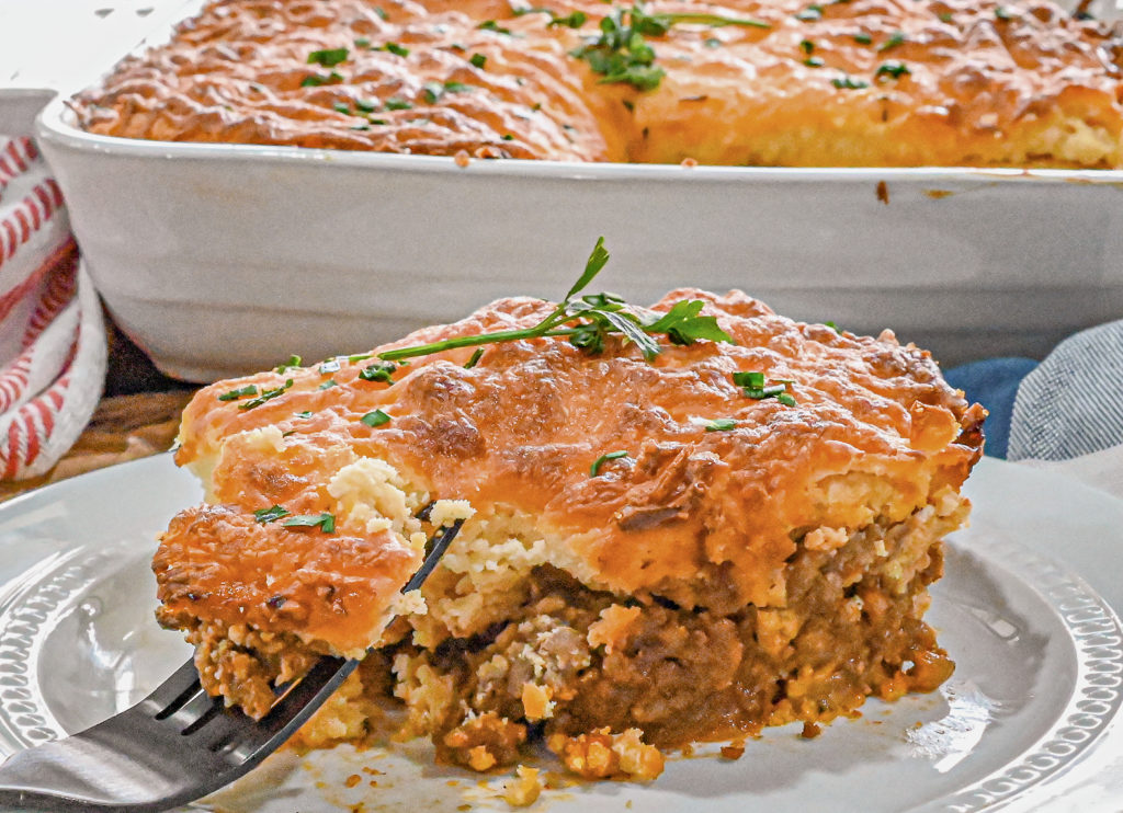 keto sloppy joe cornbread casserole served on white plate with baking dish and red and white towel in the background