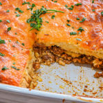 keto sloppy joe cornbread casserole swith slice missing in white baking dish up close