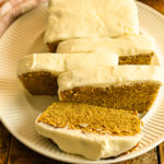 keto coconut flour pumpkin bread with cream cheese icing partially sliced on a white platter