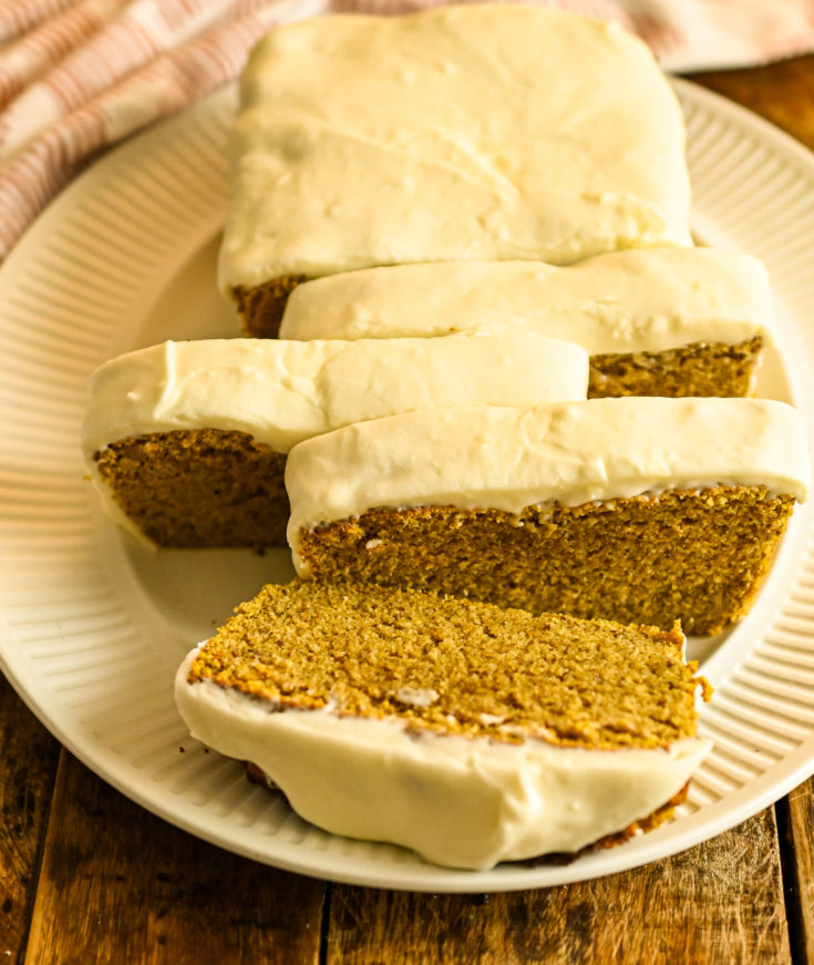 keto coconut flour pumpkin bread with cream cheese icing partially sliced on a white platter