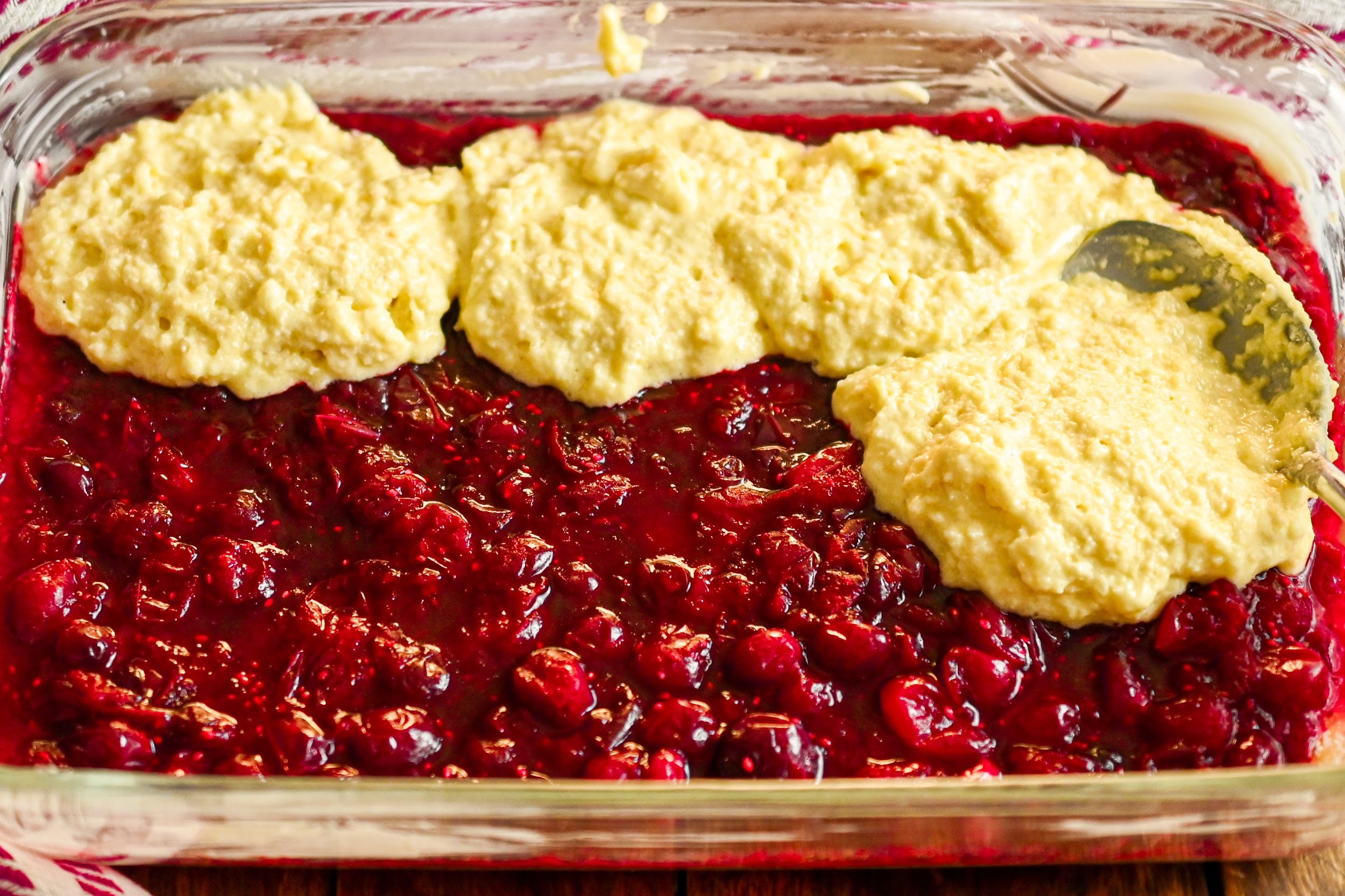 keto cranberry cobbler with the topping being added