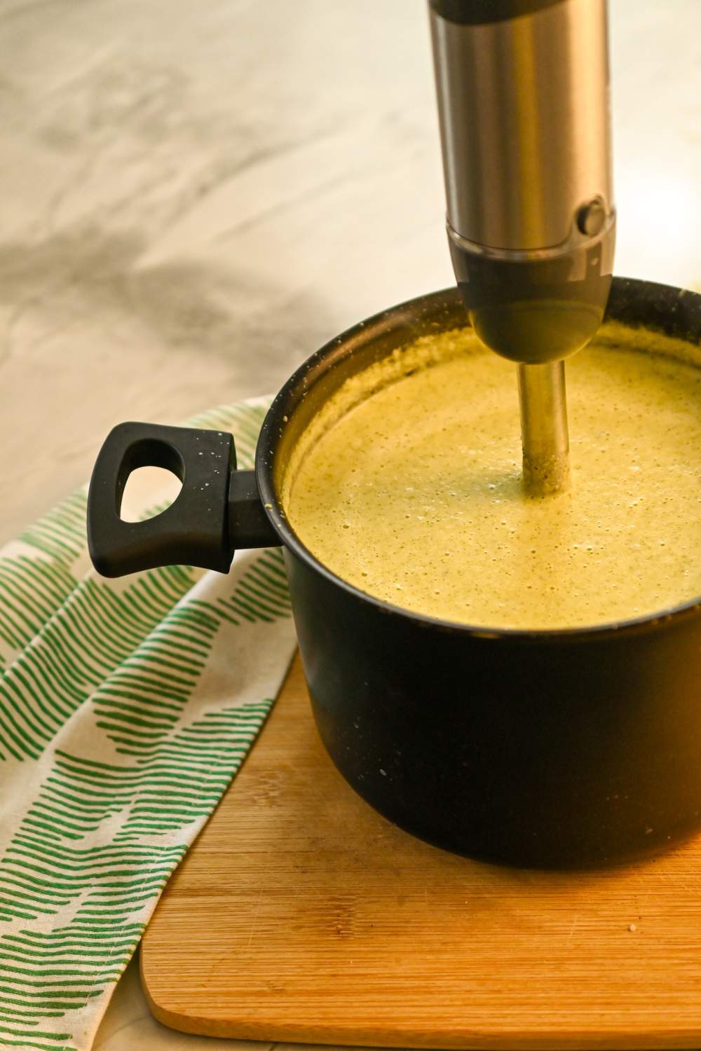 keto cream of broccoli soup being blended with an immersion blender