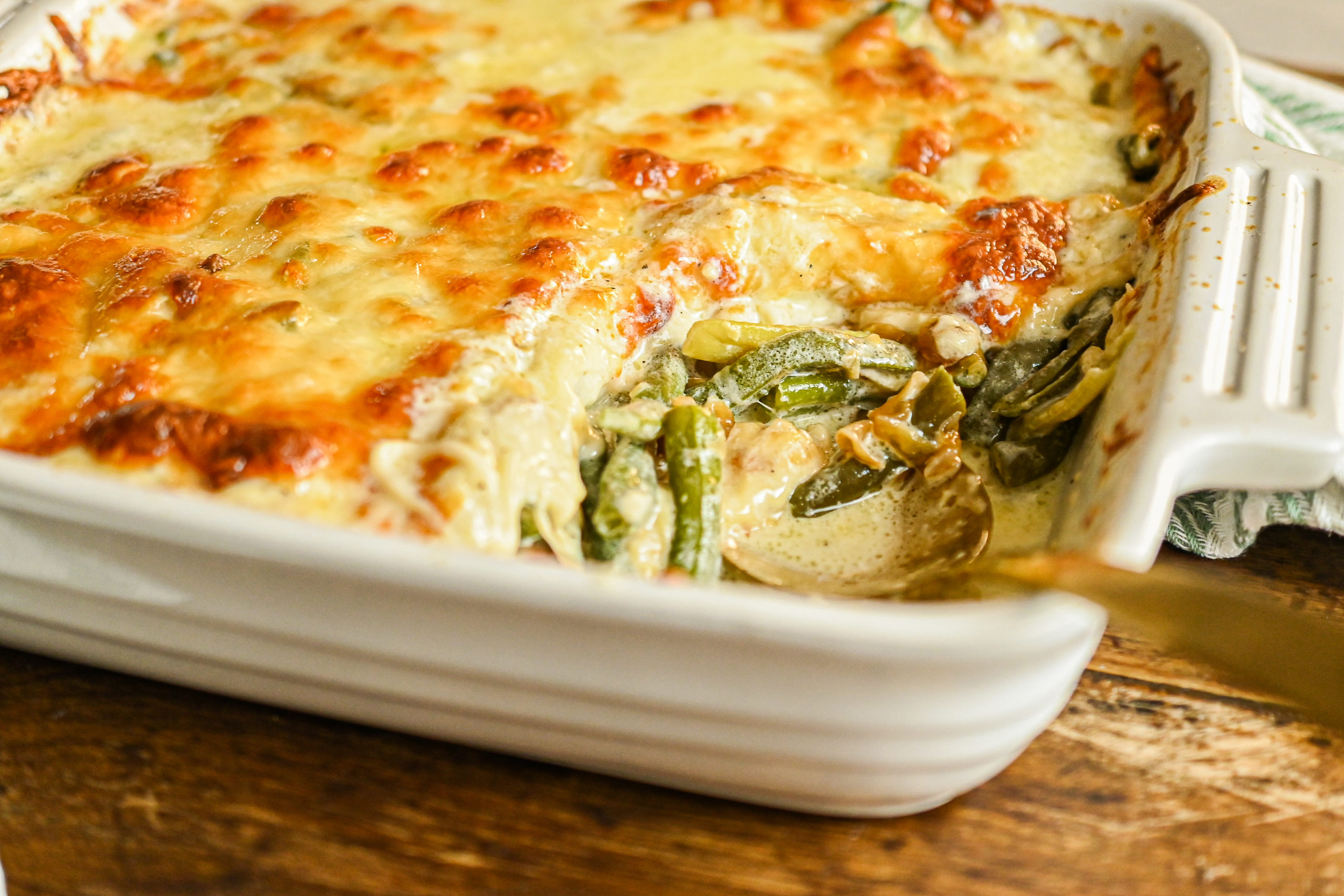 keto green bean casserole in white baking dish with copper spoon