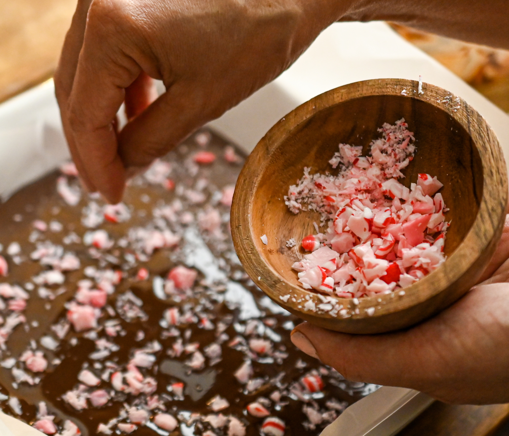Crushed sugar free peppermint candies being sprinkled on keto chocolate bark