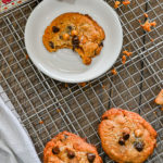 keto chocolate chip butterscotch cookies on cooling rack and bitten on white plate