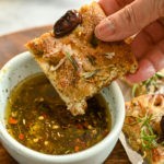 keto focaccia being dipped in seasoned olive oil dip