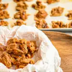 keto pralines on parchment paper with more in the background on baking sheet