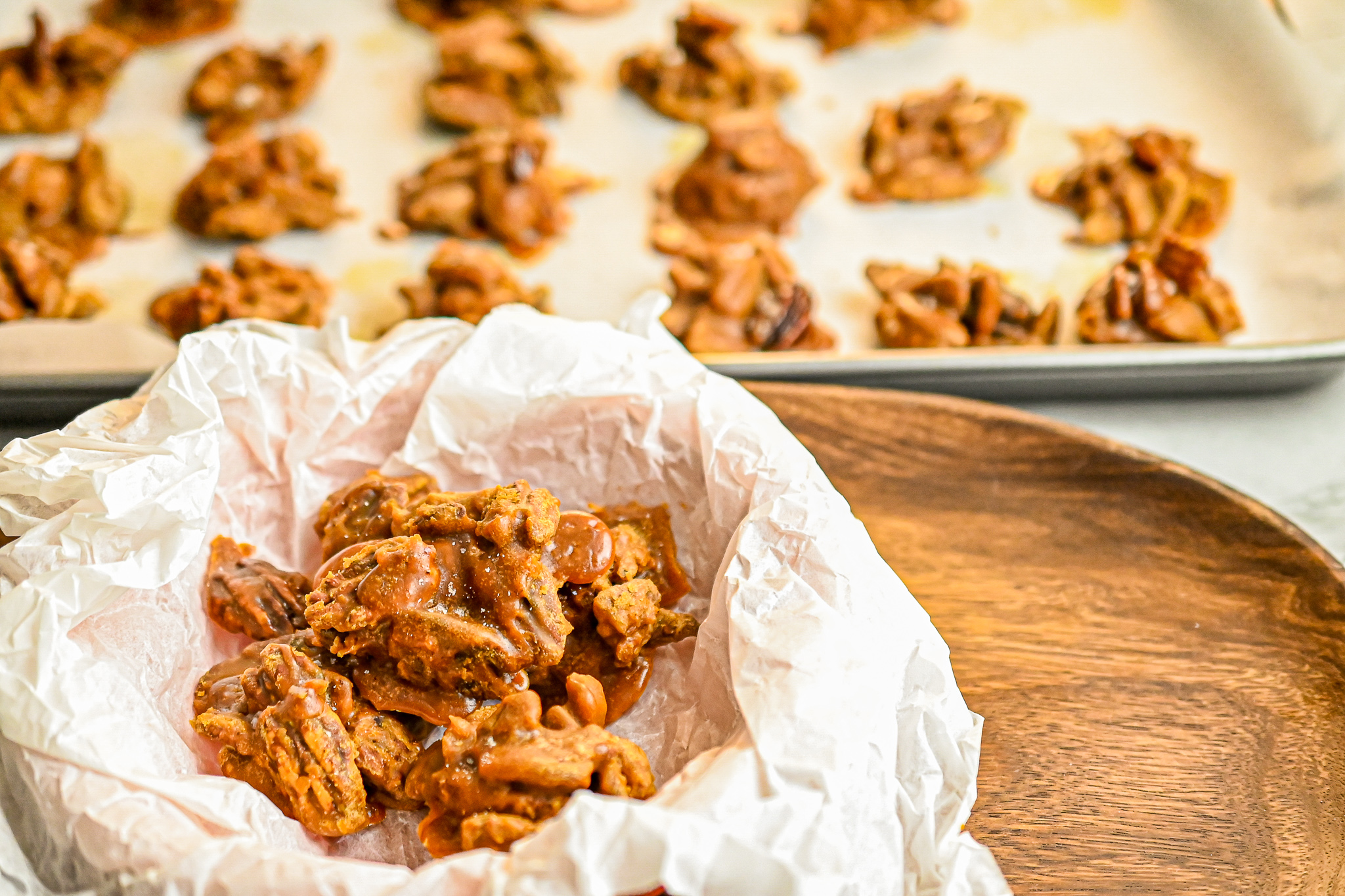 keto pralines on parchment paper with more in the background on baking sheet