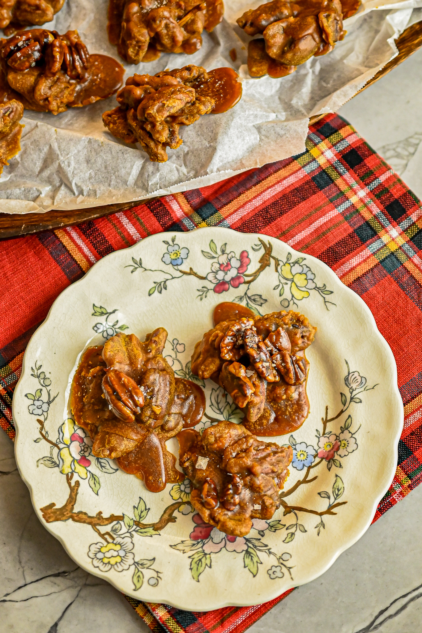 keto pralines on white decorative plate on red plaid napkin with more pralines in background