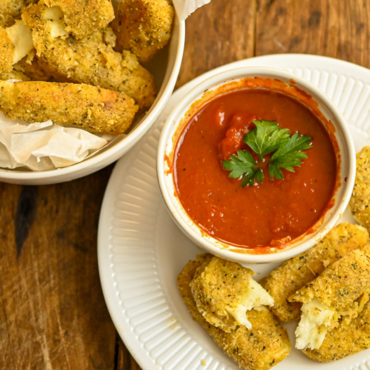 Keto Baked Mozzarella Sticks served on a white plate with marinara sauce