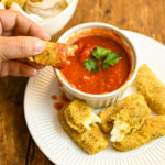 keto baked mozzarella cheese sticks dipped in marinara sauce
